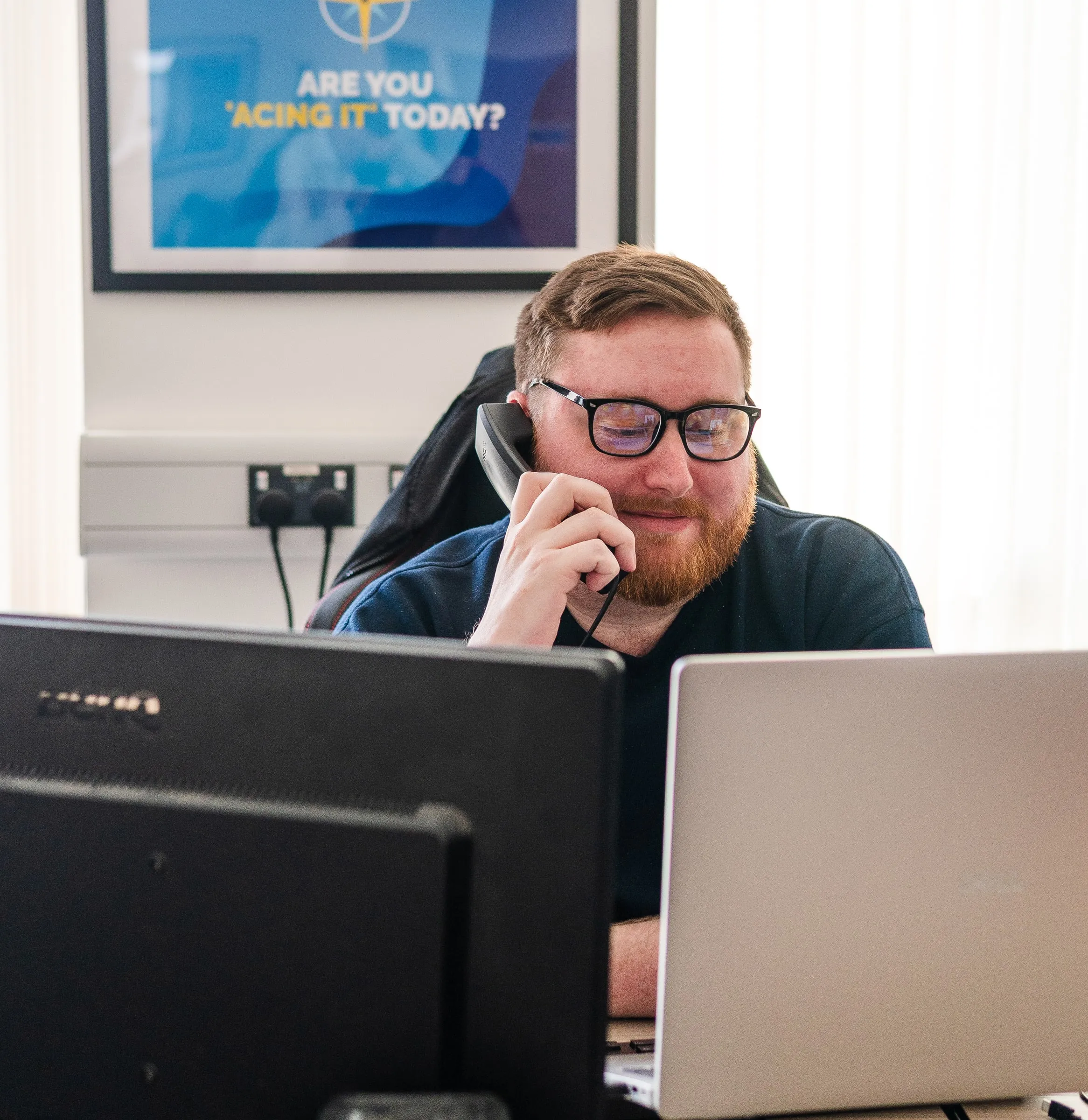 Member of ADI's office team taking a call at his desk with two screens