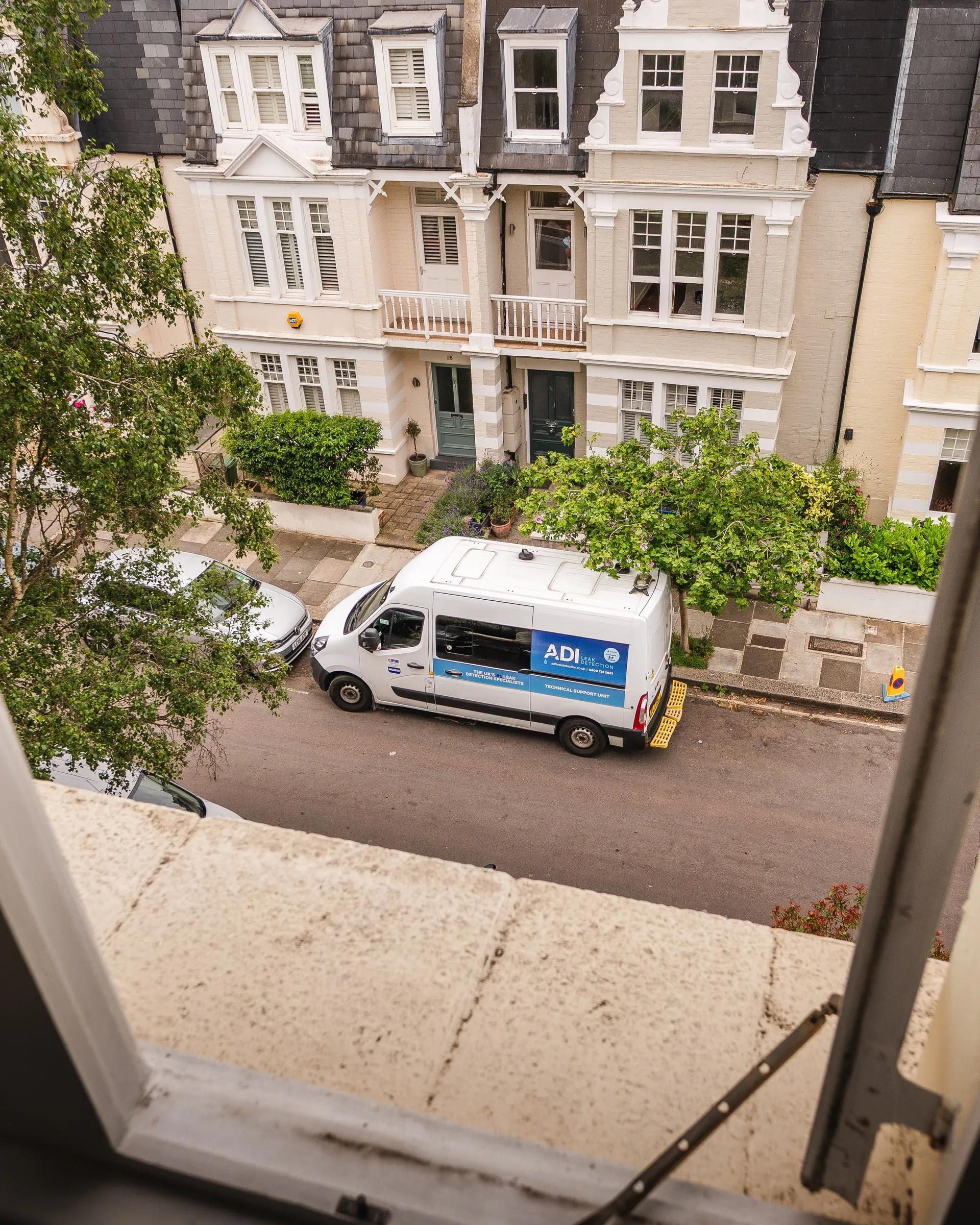 ADI van parked outside a terrace of white townhouses, seen from an upper window