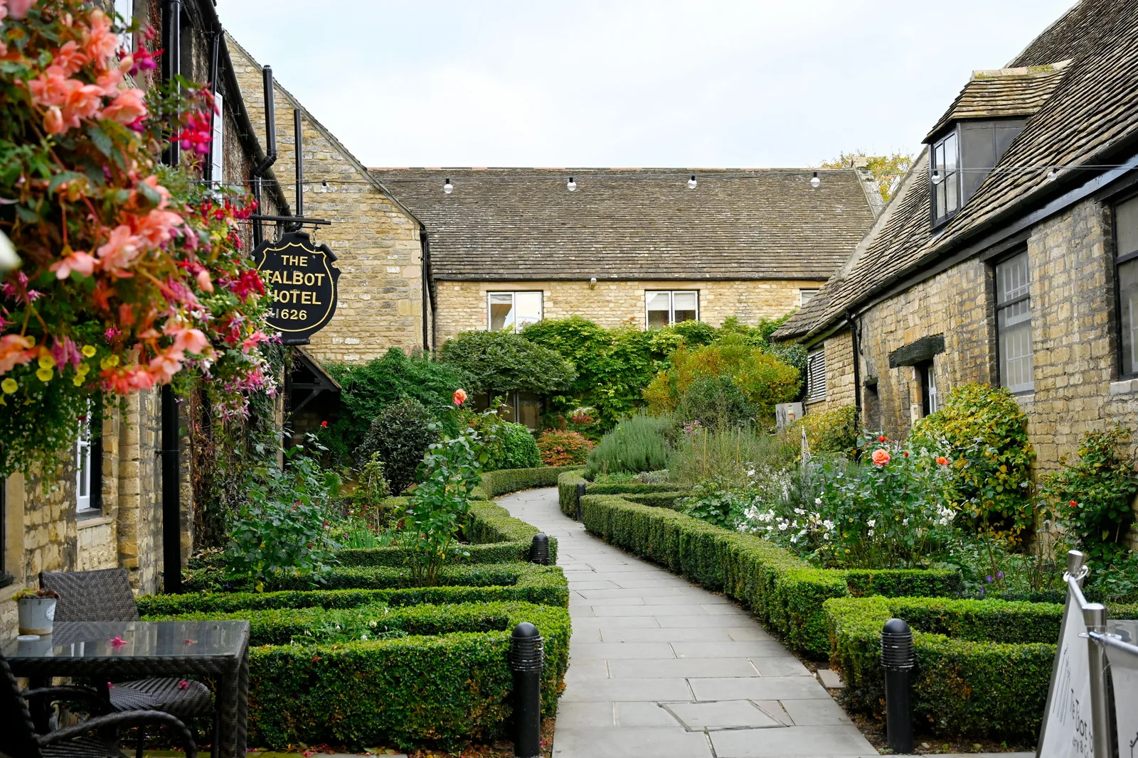 Stone hotel buildings around a landscaped courtyard with flowering gardens and a curved path